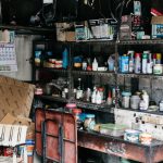 A messy garage interior showcasing shelves filled with various tools and supplies.