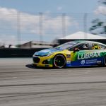 Dynamic shot of a high-speed stock car racing on a circuit, highlighting motion blur and vibrant colors.