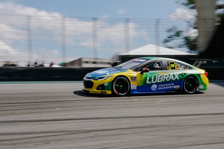 Dynamic shot of a high-speed stock car racing on a circuit, highlighting motion blur and vibrant colors.
